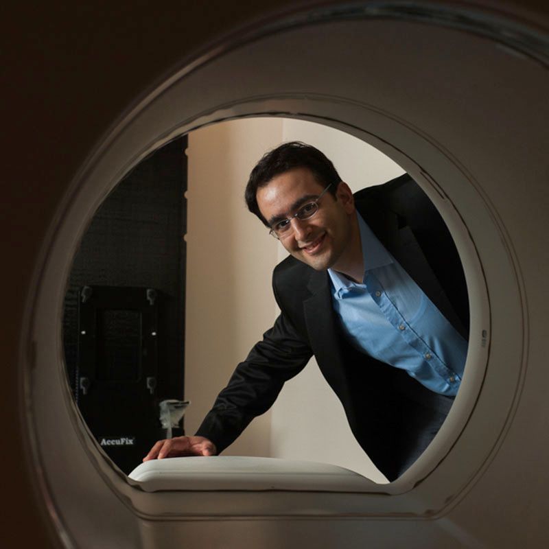 View from inside a CT or MRI-style scanner looking outward as a person leans in to inspect the device.