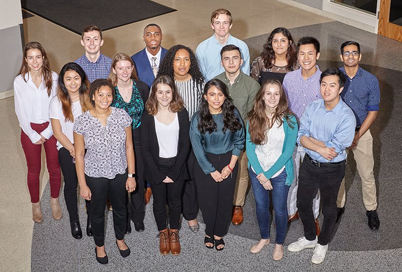 A group of people standing together indoors in a well-lit building lobby, posing for a group photo on a patterned floor.